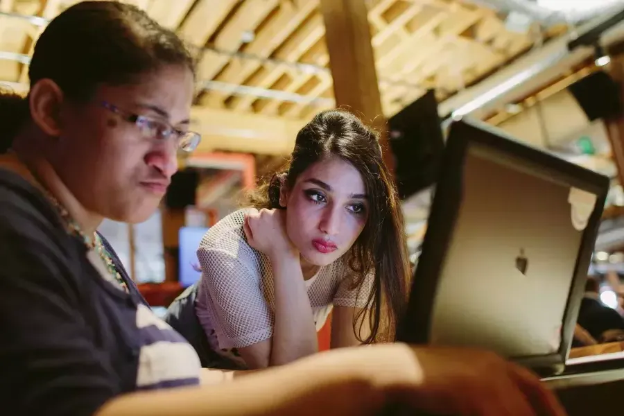 Ayman Nadeem looking over her coworker's shoulder.